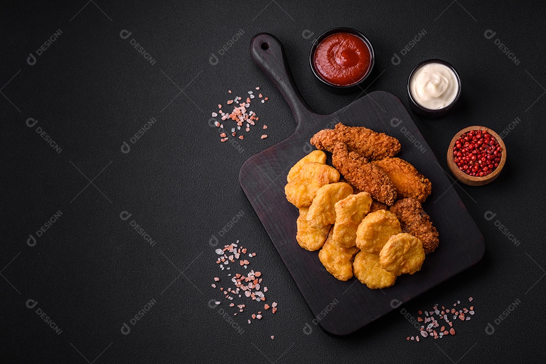 Deliciosos nuggets de frango crocantes com sal e especiarias em um fundo escuro de concreto. Comida lixo, fast-food