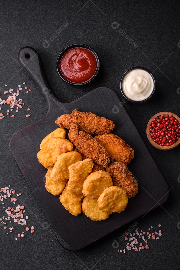 Deliciosos nuggets de frango crocantes com sal e especiarias em um fundo escuro de concreto. Comida lixo, fast-food