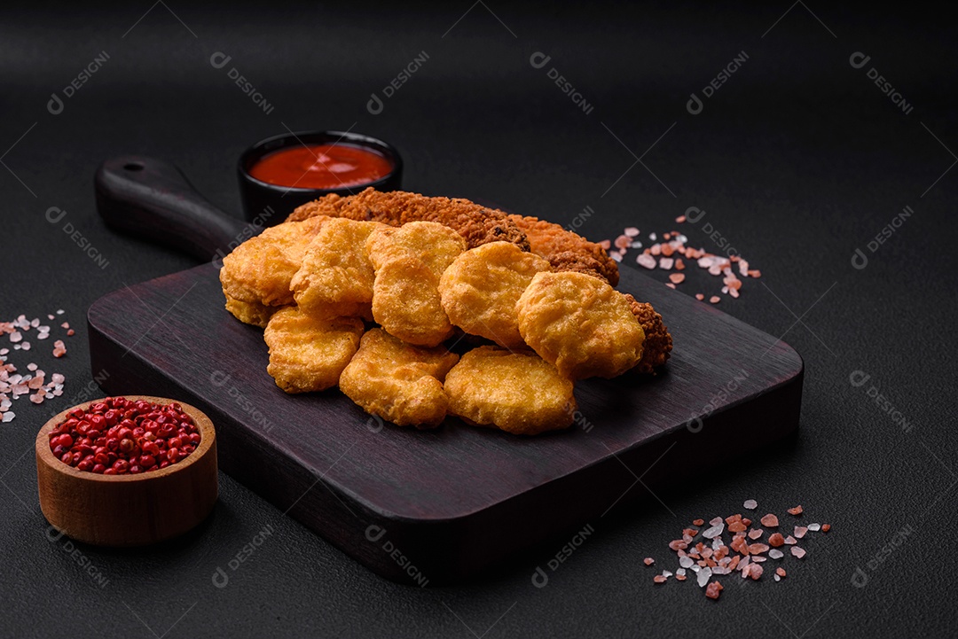 Deliciosos nuggets de frango crocantes com sal e especiarias em um fundo escuro de concreto. Comida lixo, fast-food