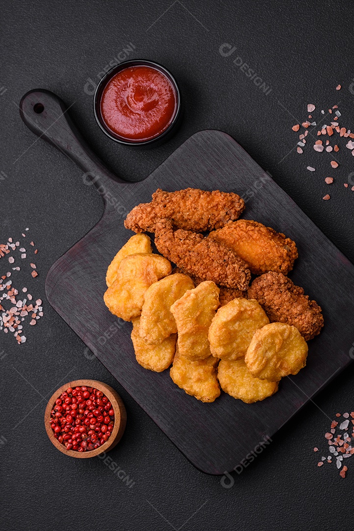 Deliciosos nuggets de frango crocantes com sal e especiarias em um fundo escuro de concreto. Comida lixo, fast-food