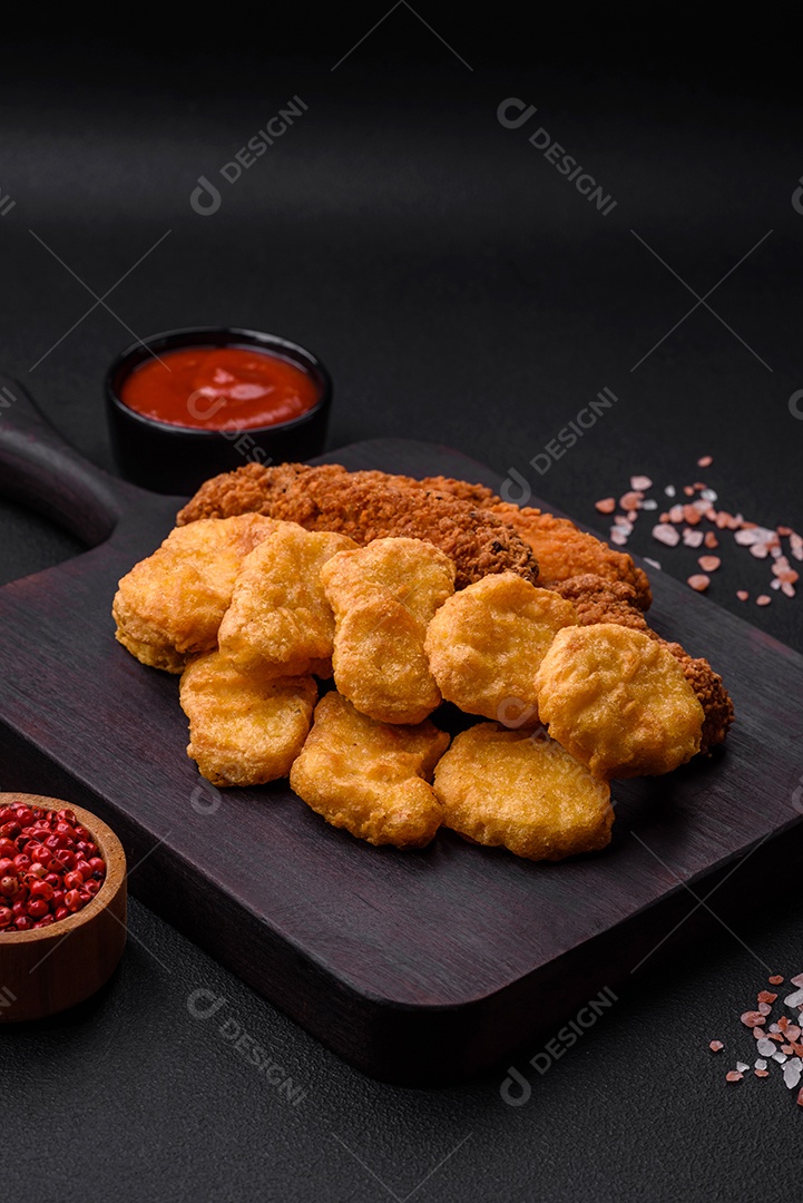 Deliciosos nuggets de frango crocantes com sal e especiarias em um fundo escuro de concreto. Comida lixo, fast-food