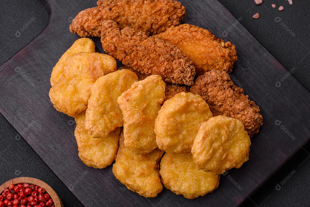 Deliciosos nuggets de frango crocantes com sal e especiarias em um fundo escuro de concreto. Comida lixo, fast-food