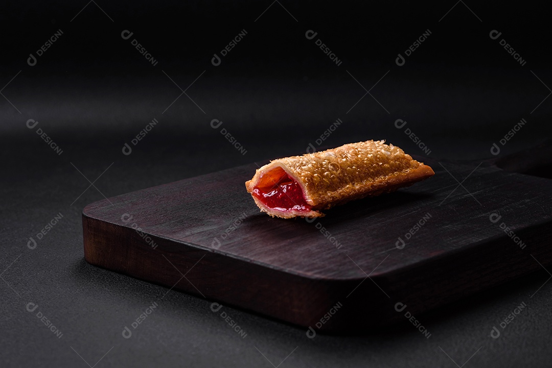 Deliciosa torta crocante fresca com geléia de cereja em uma tábua de madeira sobre um fundo escuro de concreto