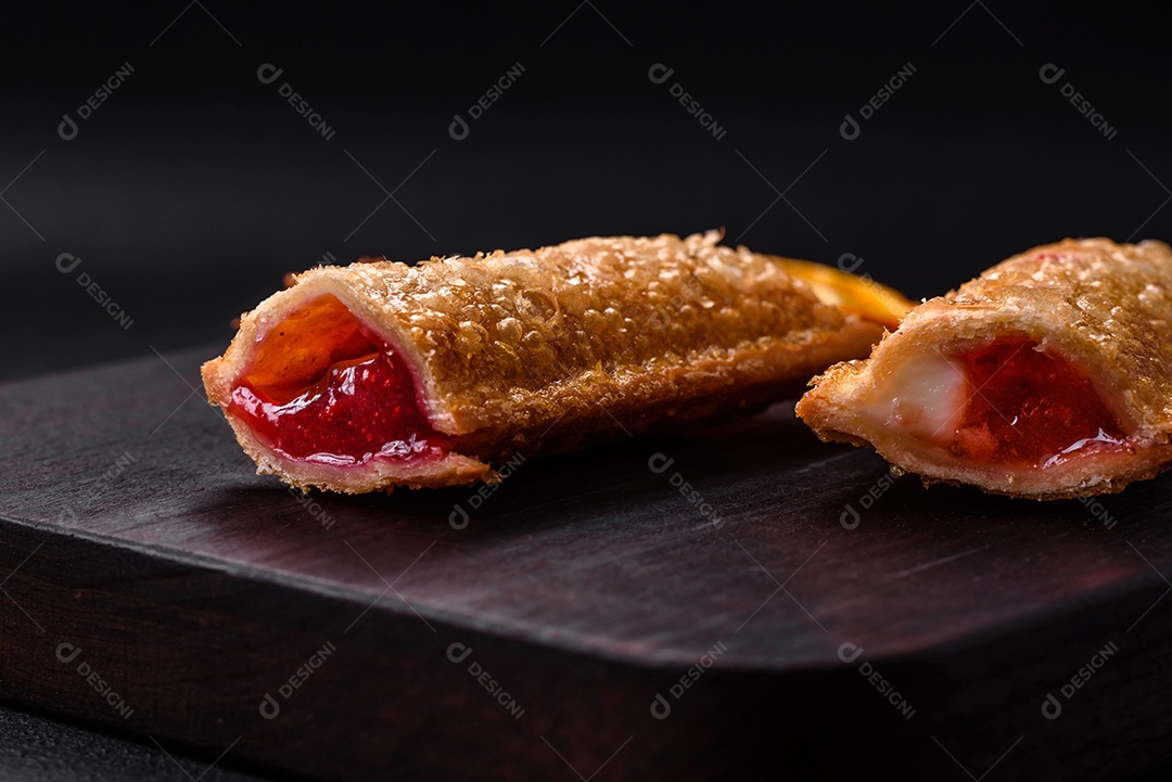 Deliciosa torta crocante fresca com geléia de cereja em uma tábua de madeira sobre um fundo escuro de concreto