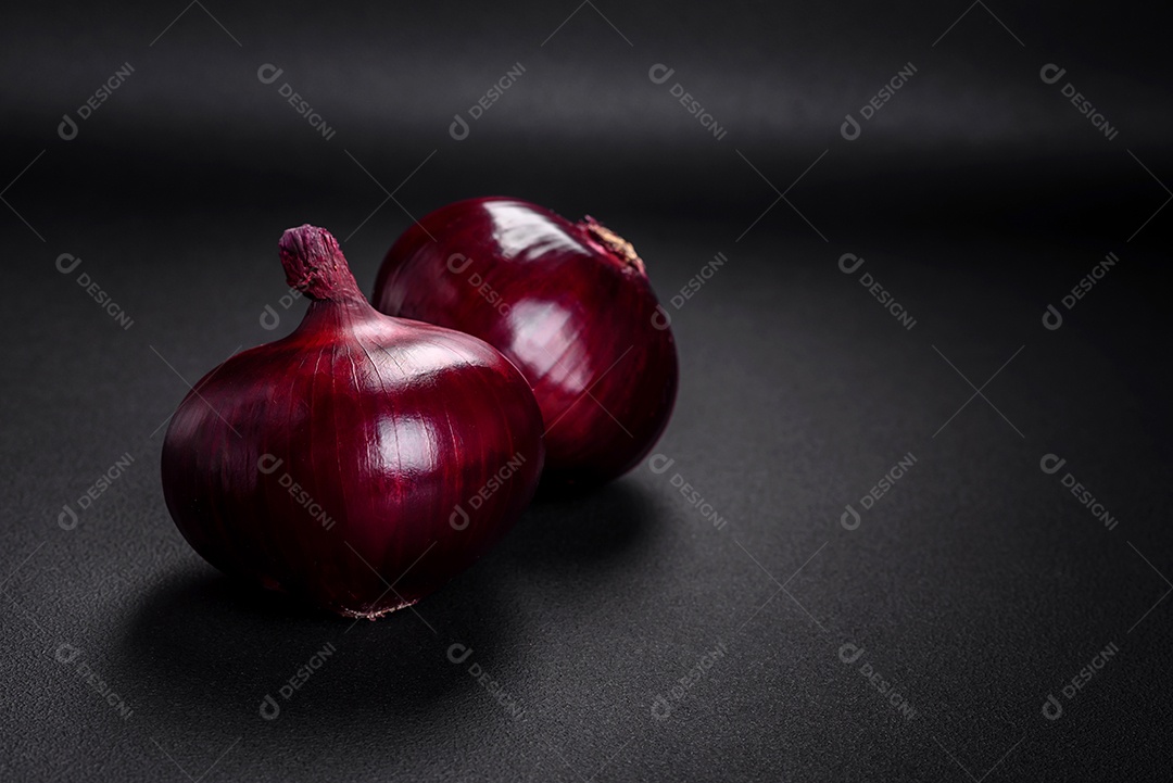 Cebolas vermelhas cruas frescas em fundo de concreto texturizado escuro. Cozinhando em casa