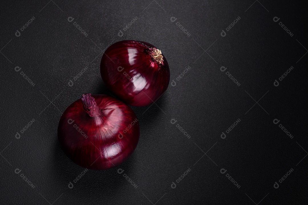 Cebolas vermelhas cruas frescas em fundo de concreto texturizado escuro. Cozinhando em casa