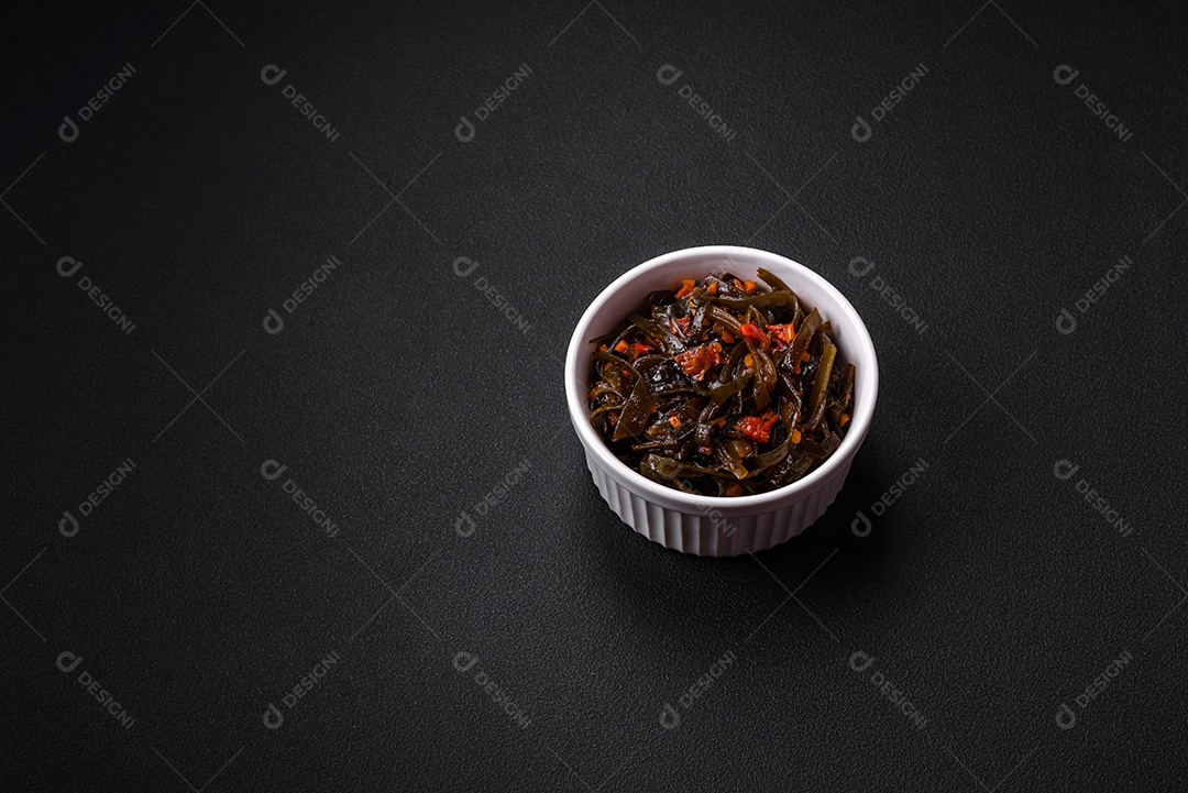 Deliciosas algas marinadas com páprica, especiarias e sal sobre um fundo escuro de concreto. Deliciosa salada vegetariana