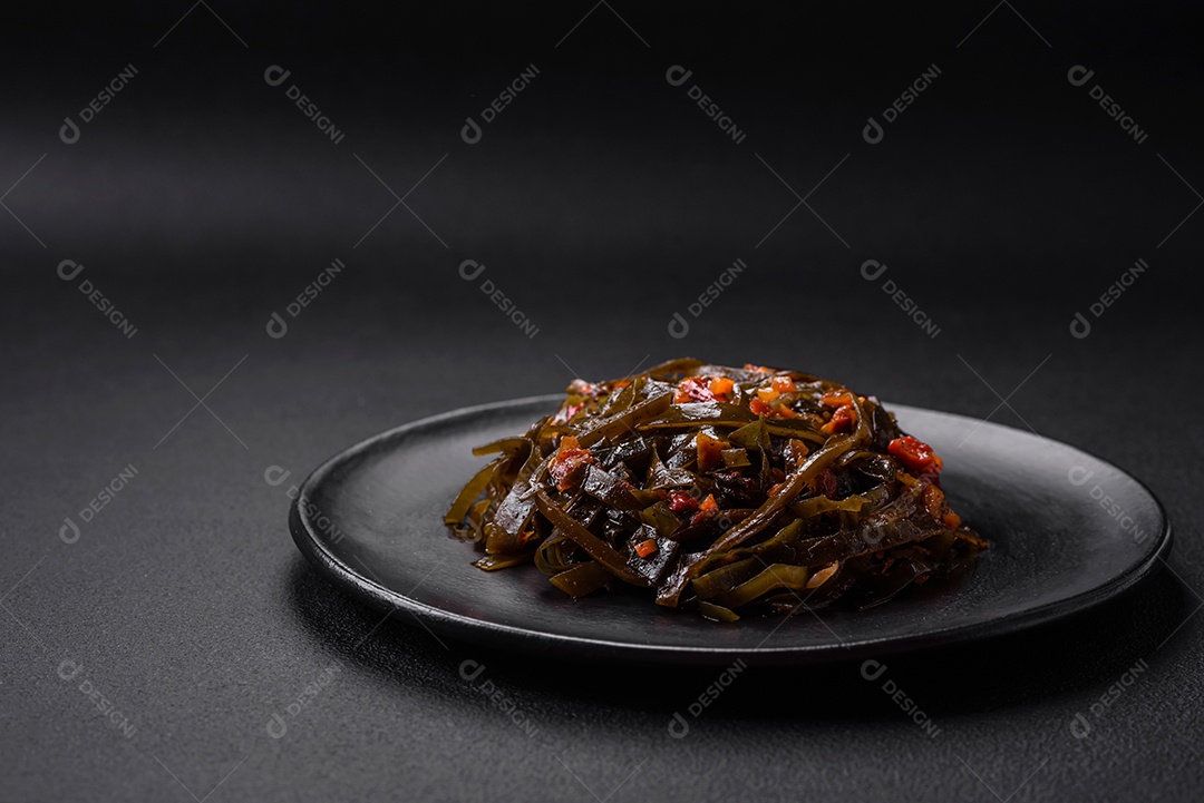 Deliciosas algas marinadas com páprica, especiarias e sal sobre um fundo escuro de concreto. Deliciosa salada vegetariana