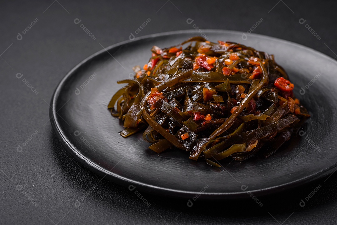 Deliciosas algas marinadas com páprica, especiarias e sal sobre um fundo escuro de concreto. Deliciosa salada vegetariana