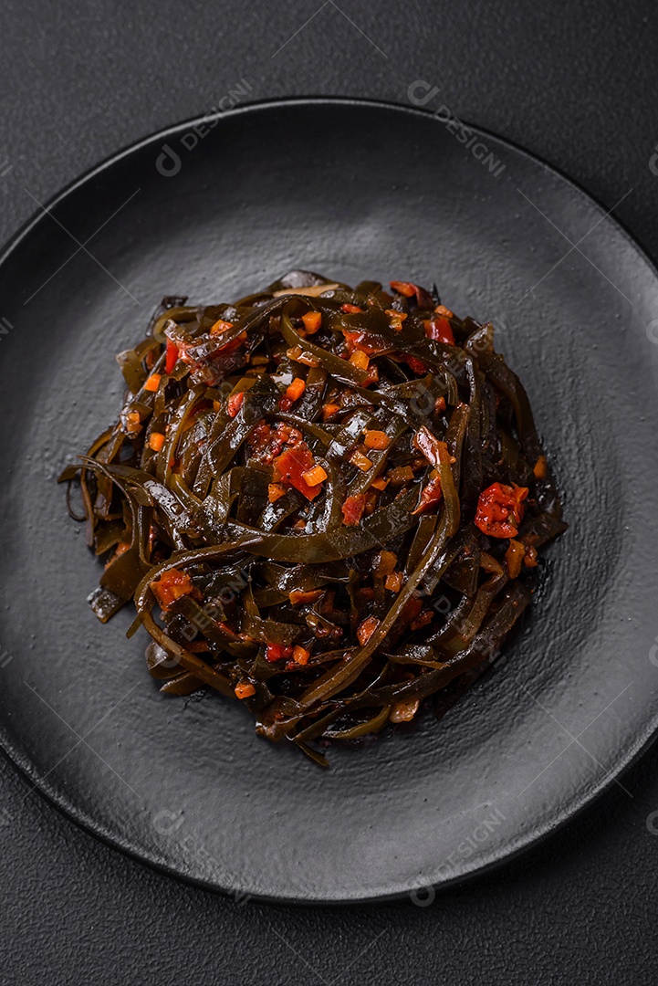 Deliciosas algas marinadas com páprica, especiarias e sal sobre um fundo escuro de concreto. Deliciosa salada vegetariana