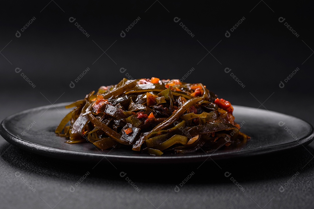 Deliciosas algas marinadas com páprica, especiarias e sal sobre um fundo escuro de concreto. Deliciosa salada vegetariana