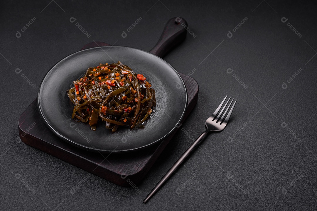 Deliciosas algas marinadas com páprica, especiarias e sal sobre um fundo escuro de concreto. Deliciosa salada vegetariana