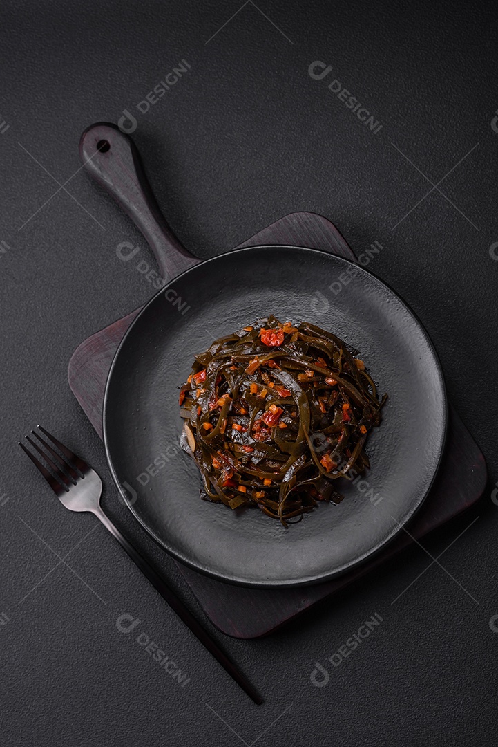 Deliciosas algas marinadas com páprica, especiarias e sal sobre um fundo escuro de concreto. Deliciosa salada vegetariana