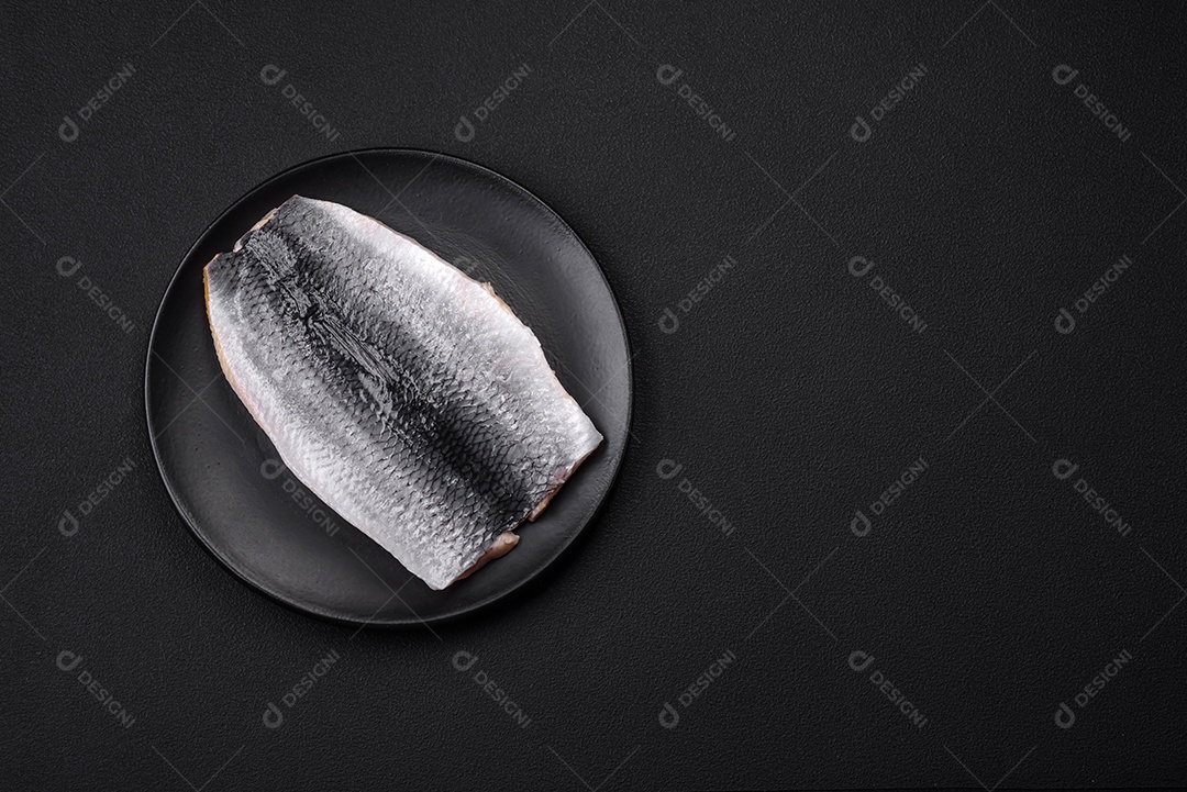 Delicioso filé de arenque salgado em óleo em uma placa de cerâmica preta sobre um fundo escuro de concreto