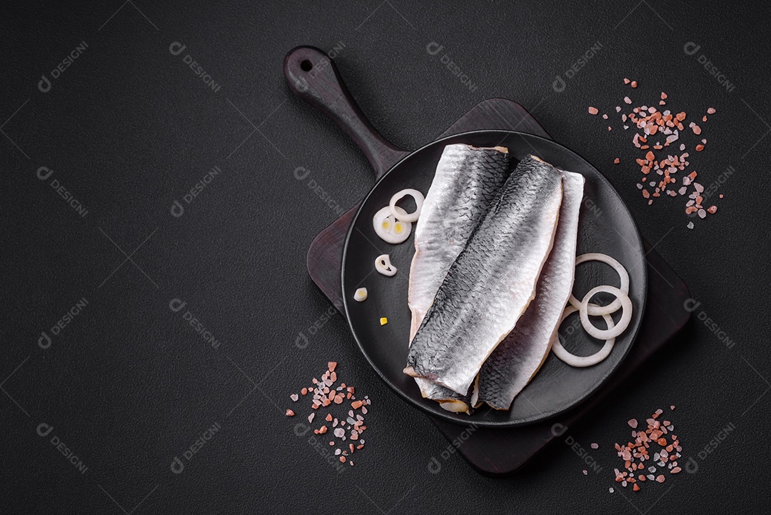 Delicioso filé de arenque salgado em óleo em uma placa de cerâmica preta sobre um fundo escuro de concreto