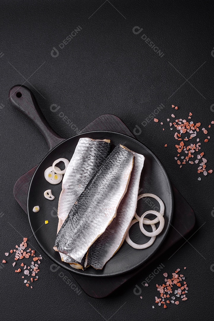 Delicioso filé de arenque salgado em óleo em uma placa de cerâmica preta sobre um fundo escuro de concreto