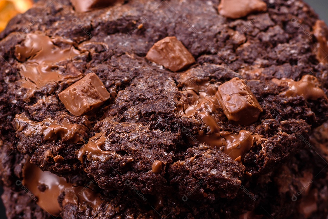 Deliciosos biscoitos redondos de aveia fresca com chocolate em uma placa de cerâmica preta sobre um fundo escuro de concreto