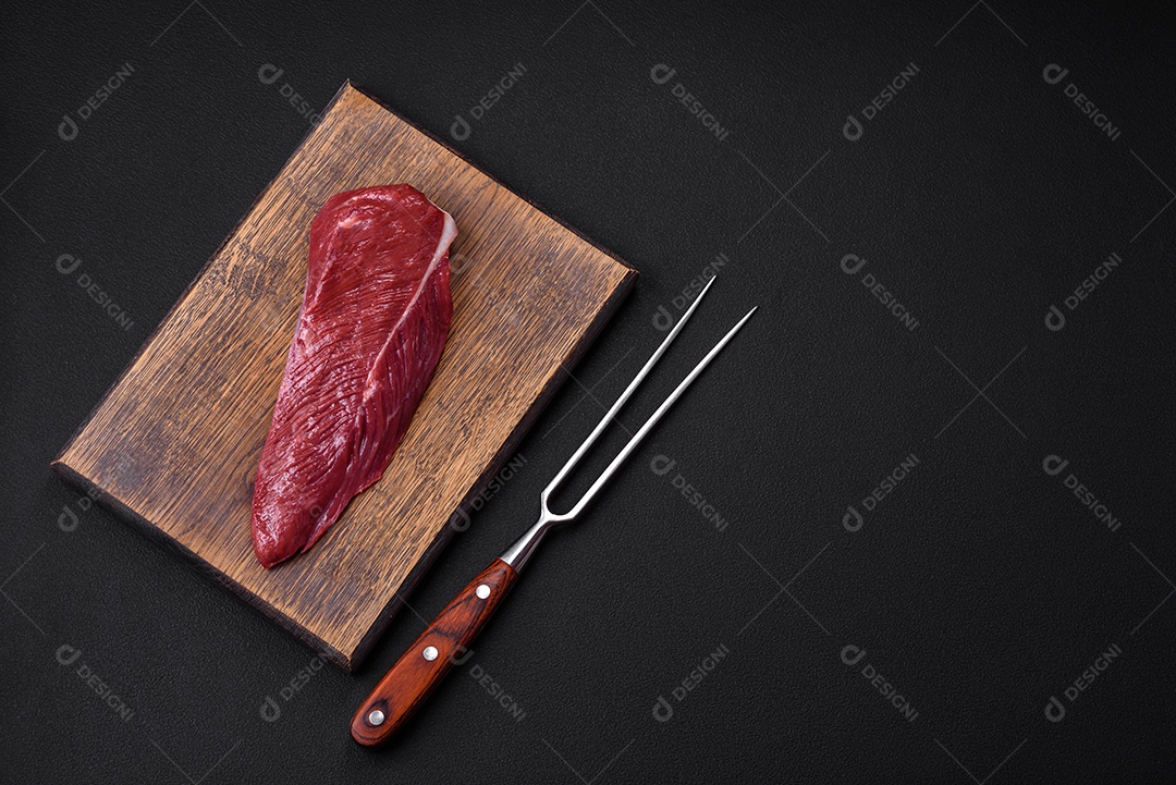 Belo pedaço fresco de carne crua em uma tábua de madeira sobre um fundo escuro de concreto