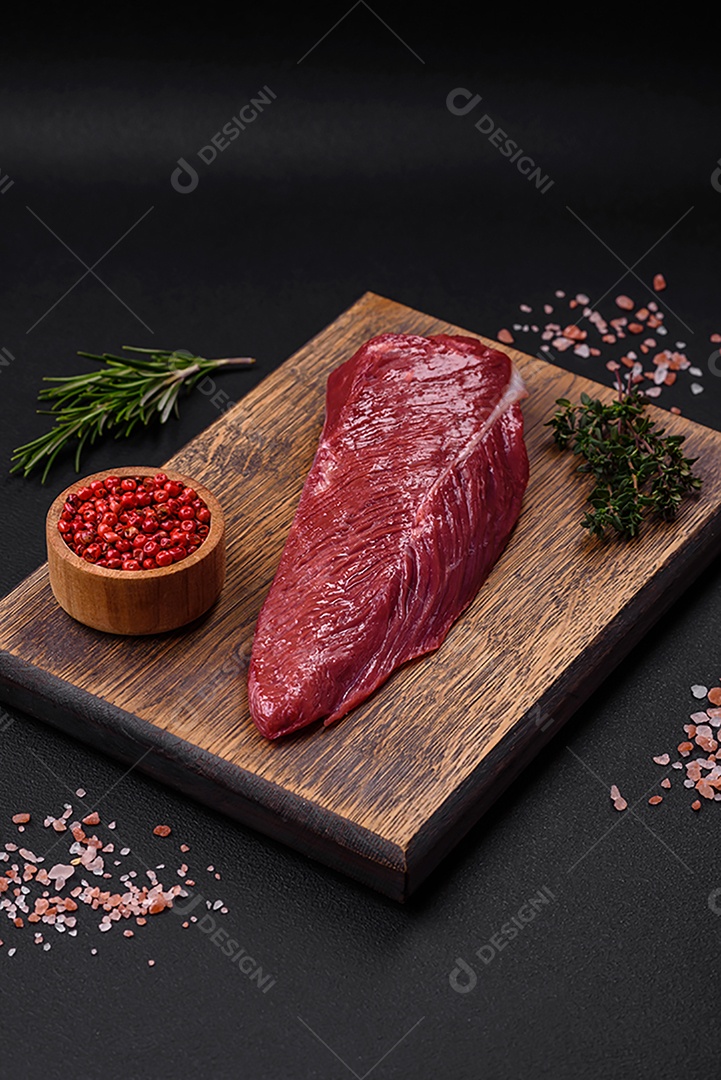 Belo pedaço fresco de carne crua em uma tábua de madeira sobre um fundo escuro de concreto