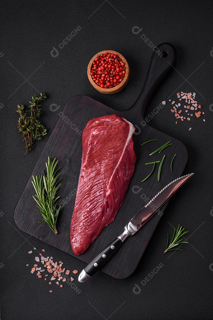 Belo pedaço fresco de carne crua em uma tábua de madeira sobre um fundo escuro de concreto
