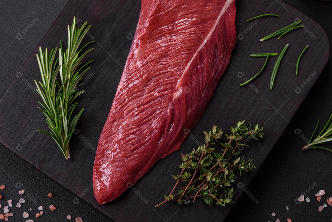 Belo pedaço fresco de carne crua em uma tábua de madeira sobre um fundo escuro de concreto