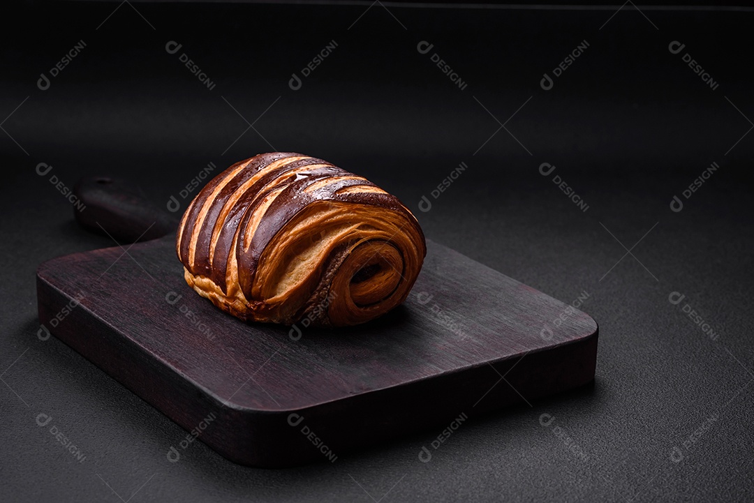 Delicioso pão de canela assado fresco e crocante em fundo escuro de concreto