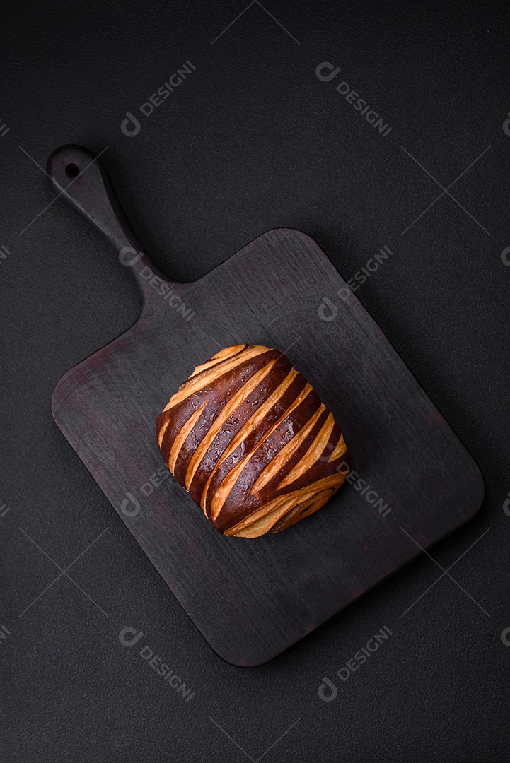 Delicioso pão de canela assado fresco e crocante em fundo escuro de concreto