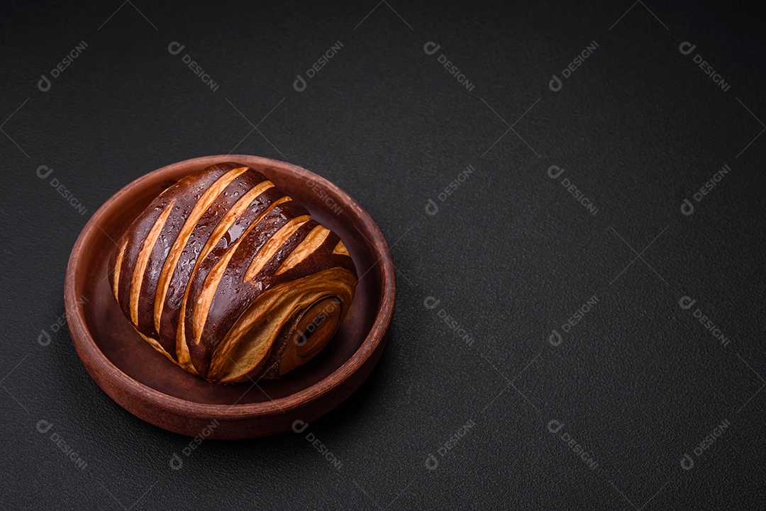 Delicioso pão de canela assado fresco e crocante em fundo escuro de concreto