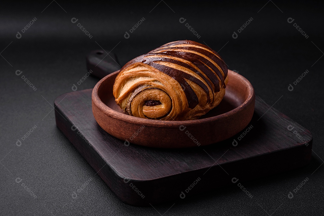 Delicioso pão de canela assado fresco e crocante em fundo escuro de concreto