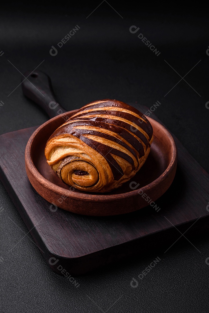 Delicioso pão de canela assado fresco e crocante em fundo escuro de concreto