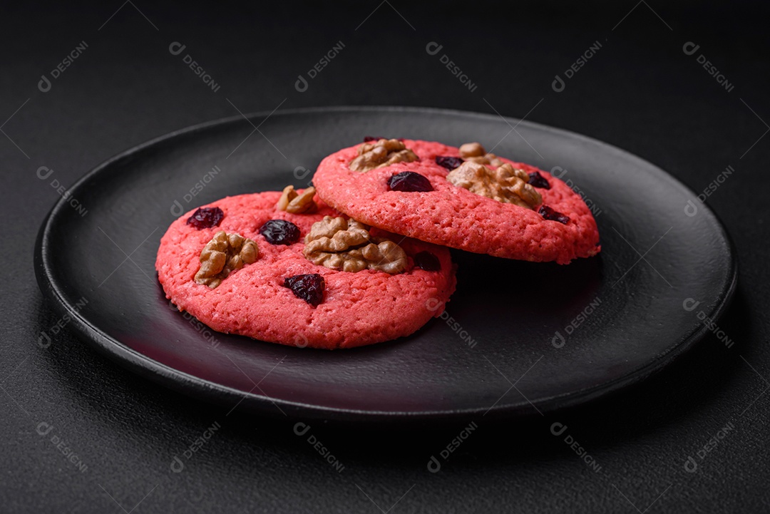 Deliciosos biscoitos de aveia rosa crocantes e frescos com sabor de framboesa sobre um fundo escuro de concreto