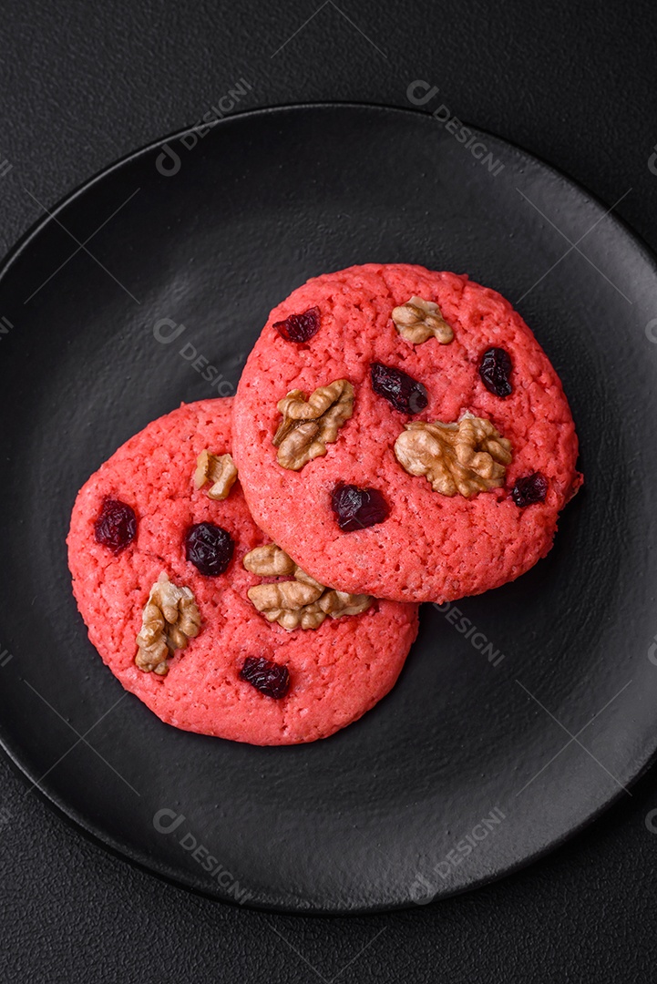 Deliciosos biscoitos de aveia rosa crocantes e frescos com sabor de framboesa sobre um fundo escuro de concreto