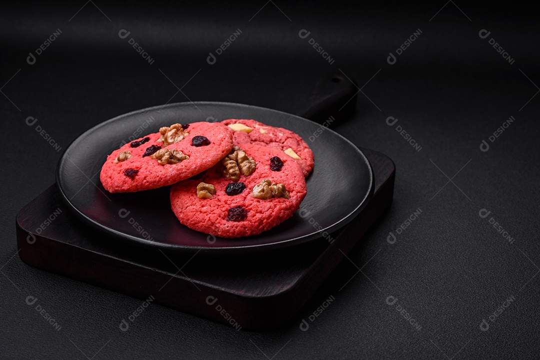 Deliciosos biscoitos de aveia rosa crocantes e frescos com sabor de framboesa sobre um fundo escuro de concreto