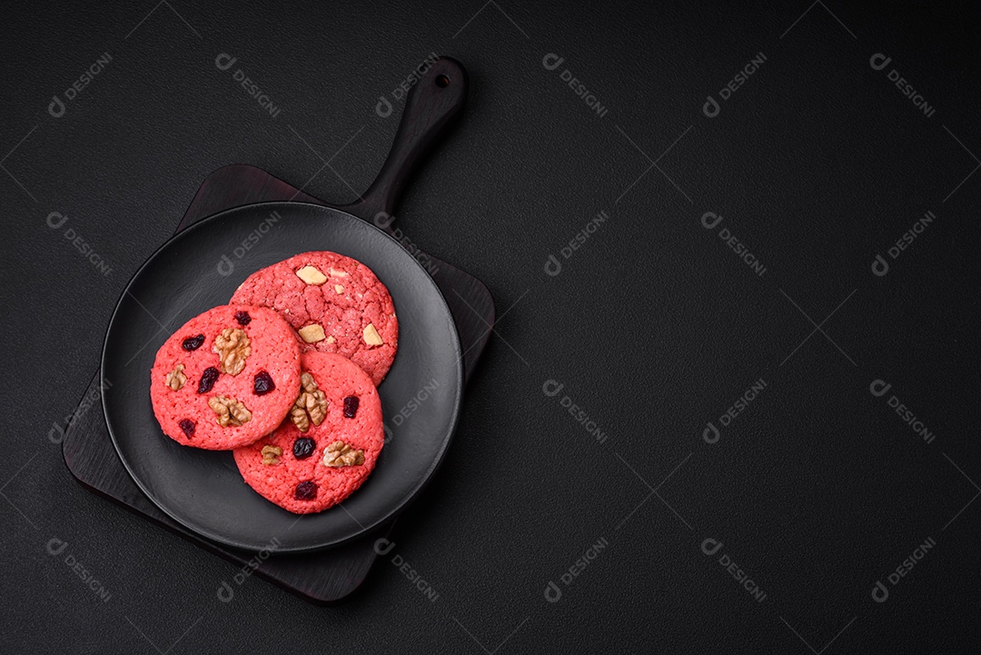 Deliciosos biscoitos de aveia rosa crocantes e frescos com sabor de framboesa sobre um fundo escuro de concreto