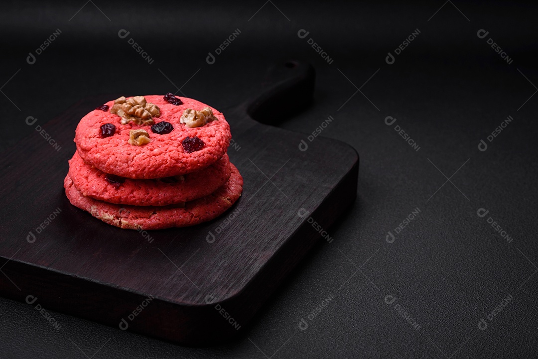 Deliciosos biscoitos de aveia rosa crocantes e frescos com sabor de framboesa sobre um fundo escuro de concreto