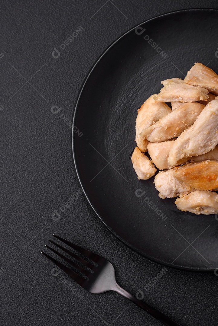 Deliciosas fatias de frango assadas com especiarias e ervas em uma placa cerâmica redonda sobre um fundo escuro de concreto