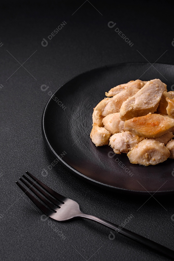 Deliciosas fatias de frango assadas com especiarias e ervas em uma placa cerâmica redonda sobre um fundo escuro de concreto