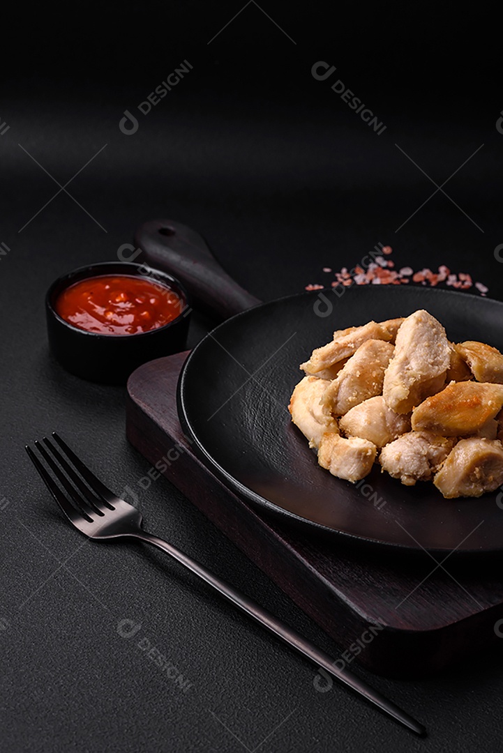 Deliciosas fatias de frango assadas com especiarias e ervas em uma placa cerâmica redonda sobre um fundo escuro de concreto