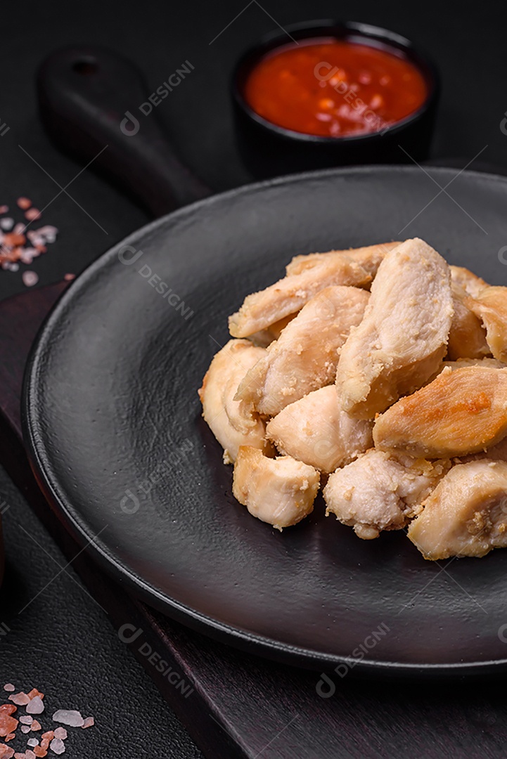 Deliciosas fatias de frango assadas com especiarias e ervas em uma placa cerâmica redonda sobre um fundo escuro de concreto