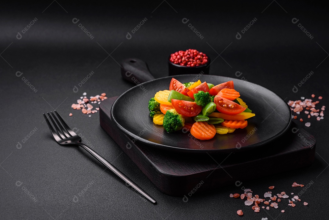 Salada de legumes frescos e cozidos no vapor, tomate cereja, brócolis, cenoura e feijão de espargos sobre um fundo escuro de concreto