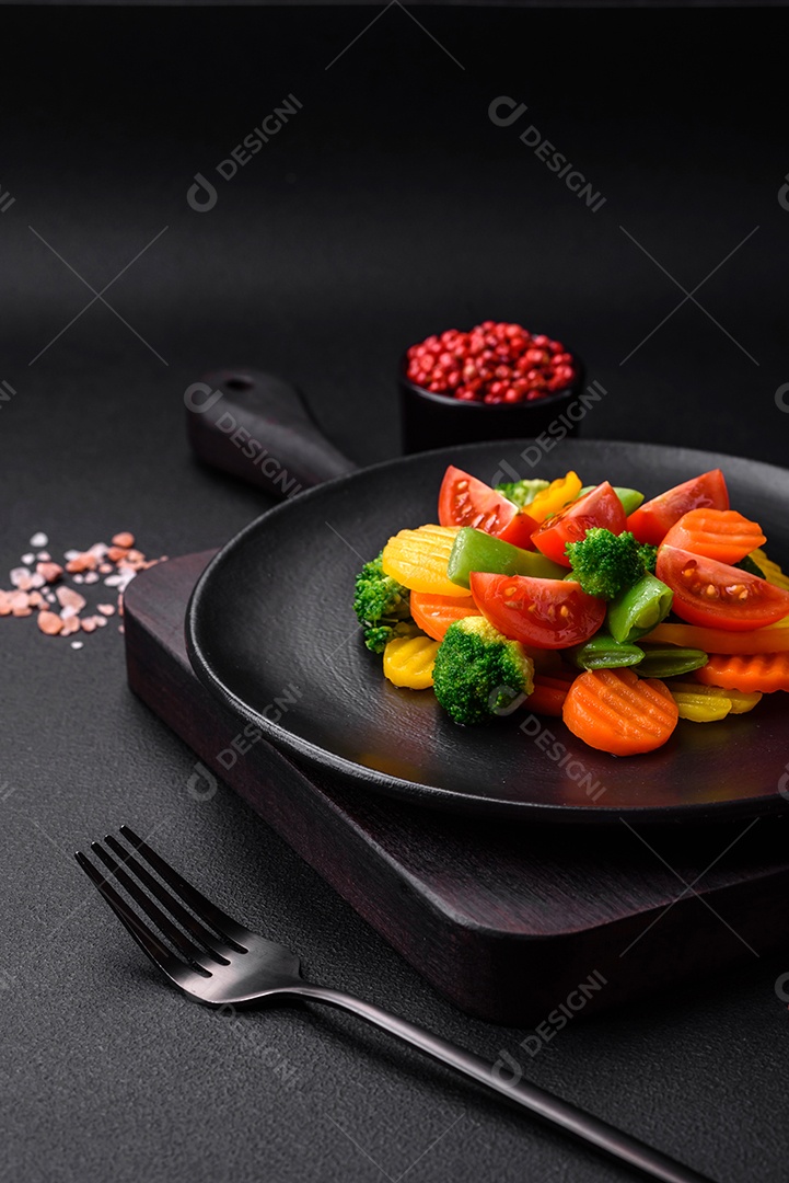 Salada de legumes frescos e cozidos no vapor, tomate cereja, brócolis, cenoura e feijão de espargos sobre um fundo escuro de concreto