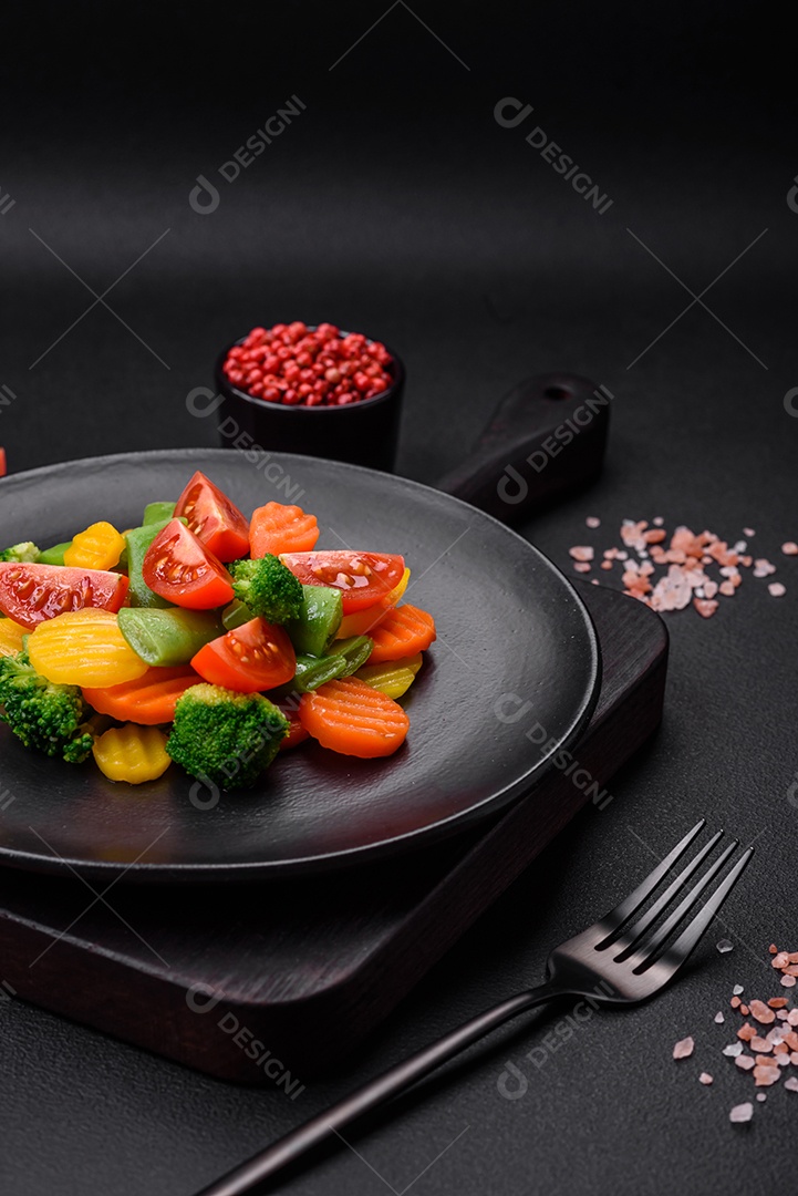 Salada de legumes frescos e cozidos no vapor, tomate cereja, brócolis, cenoura e feijão de espargos sobre um fundo escuro de concreto
