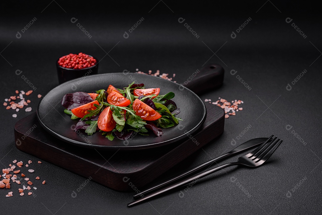 Salada de tomate cereja fresco, rúcula, espinafre, folhas jovens de beterraba e outras verduras sobre fundo escuro de concreto