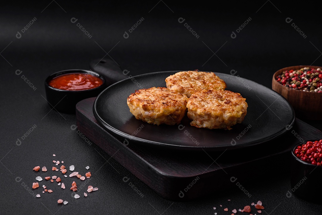 Deliciosas costeletas ou almôndegas frescas com especiarias e ervas sobre um fundo escuro de concreto