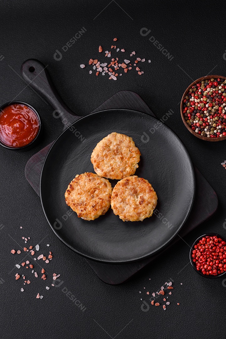 Deliciosas costeletas ou almôndegas frescas com especiarias e ervas sobre um fundo escuro de concreto