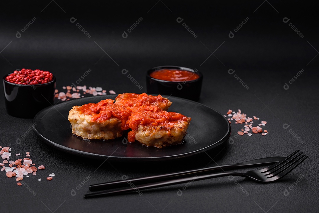 Deliciosas costeletas ou almôndegas frescas com especiarias, ervas e molho de tomate sobre um fundo escuro de concreto