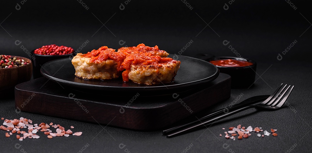 Deliciosas costeletas ou almôndegas frescas com especiarias, ervas e molho de tomate sobre um fundo escuro de concreto