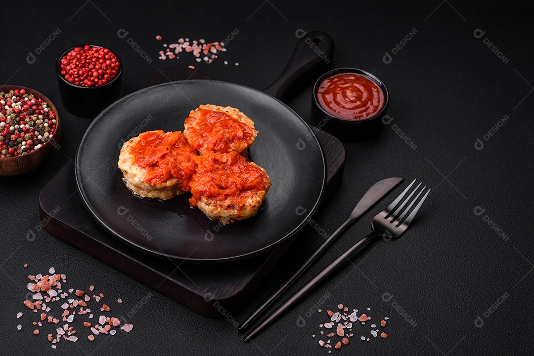 Deliciosas costeletas ou almôndegas frescas com especiarias, ervas e molho de tomate sobre um fundo escuro de concreto