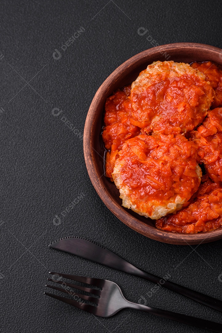 Deliciosas costeletas ou almôndegas frescas com especiarias, ervas e molho de tomate sobre um fundo escuro de concreto