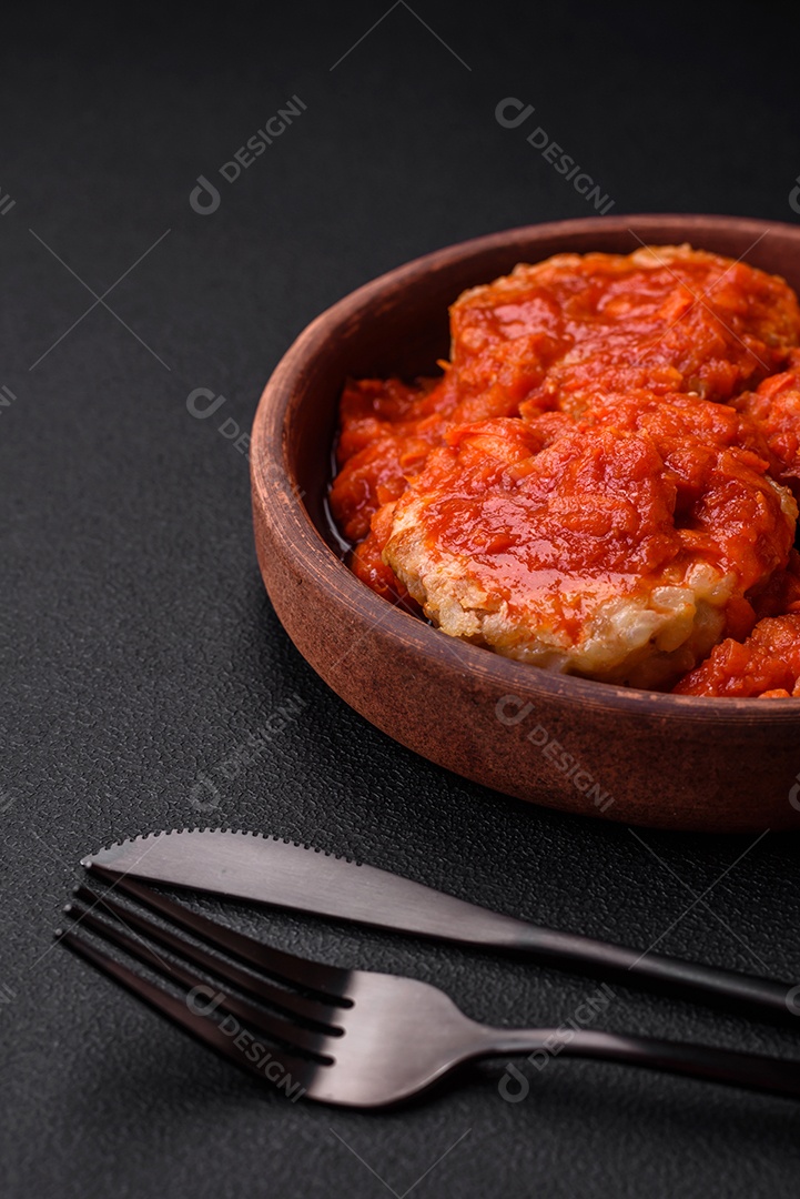 Deliciosas costeletas ou almôndegas frescas com especiarias, ervas e molho de tomate sobre um fundo escuro de concreto